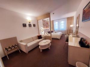 a living room with a couch and a bed at Hotel Slamený Dom & SPA in Košice