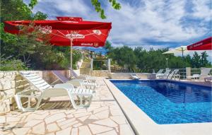 a pool with white chairs and a red umbrella and a pool at 10 Bedroom Beautiful Home In Kucice in Kučiće
