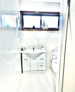 a white bathroom with a sink and a toilet at Guest Room in Kealba in St Albans