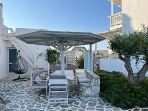 a patio with a table and chairs under a umbrella at Village Liana Marouli Kastraki 2 in Kastraki Naxou