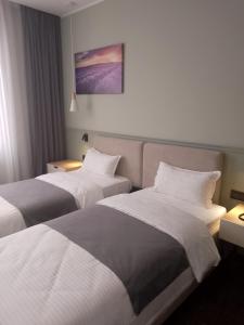 a hotel room with two beds with white sheets at Caspian Marine Hotel in Aktau