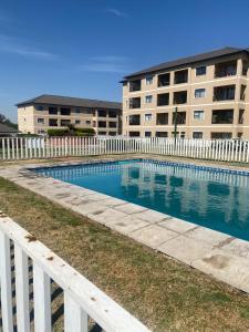 a swimming pool with a white fence and a building at Royal reef West in Boksburg