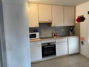 a kitchen with white cabinets and a microwave at Les Renardeaux in Malmedy