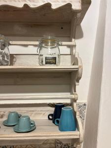 un estante con tazas y un frasco de cristal. en Trulli Abate Mauro, en Cisternino