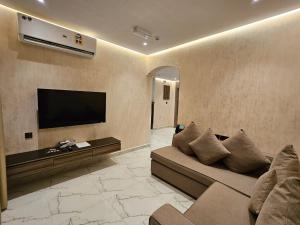 a living room with a couch and a flat screen tv at Royal Plaza Hotel in Duqm