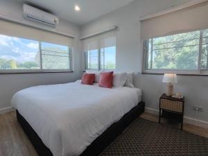 a bedroom with a large white bed with two windows at The Well House By Dao in Ban Doi Hang