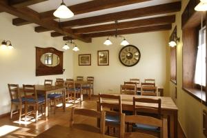 a dining room with tables and chairs and a clock at Casa Felisa Pirineo Aragonés in Santa Eulalia de Gállego