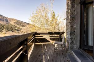 a chair sitting on a wooden porch with a window at Les GRANDS SORBIERS à Méribel - Charmant studio situé à 2 pas des pistes & du centre de Méribel in Les Allues