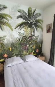 a bedroom with a bed with a palm tree mural at Le nid du lac in Marciac