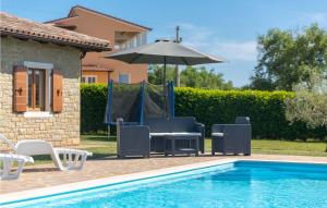 a group of chairs and an umbrella next to a pool at Villa Ciano in Višnjan
