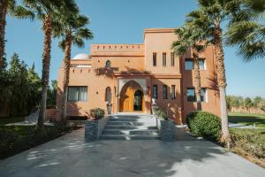a building with palm trees in front of it at DAR KAYIS & LAILA in Marrakesh