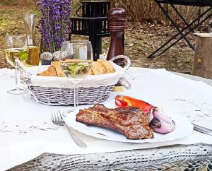 una mesa con un plato de carne y una cesta de pan en Forest Hide Tiny House, en Covasna 27 fotos más