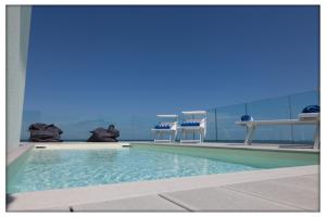 a swimming pool with two chairs in a room at Hotel Madalù in Rimini