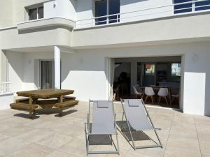 2 Stühle und ein Picknicktisch auf einer Terrasse in der Unterkunft Villa face mer avec terrasse in Merlimont