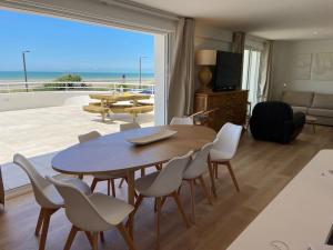a dining room with a table and chairs and a view of the beach at Villa face mer avec terrasse in Merlimont