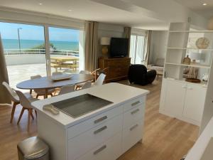 eine Küche und ein Wohnzimmer mit einem Tisch und Meerblick in der Unterkunft Villa face mer avec terrasse in Merlimont