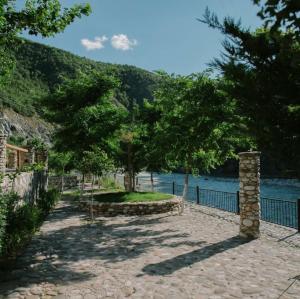 a walkway with trees and a fence next to the water at Restauraunt-Kalaja in (( Bokaj ))