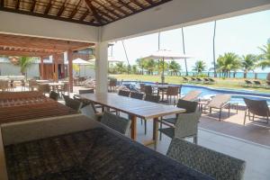 un ristorante con tavoli e sedie e una piscina di Village do Mar Itacimirim pé na areia a Camassari