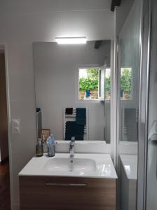 a white bathroom with a sink and a mirror at Coté mer in Le Croisic