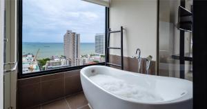 a bath tub in a bathroom with a large window at Siam At Siam Design Hotel Pattaya in Pattaya