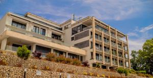 a large white building behind a stone wall at MyFreedom Panorama Cubana Apartment in Alsóörs