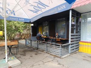 two men sitting at tables outside of a restaurant at Хостел Sweet Home in Mykolaiv