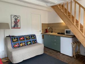 a room with a bed and a kitchen with a staircase at La Maison de Maud in Chaise-Dieu-du-Theil