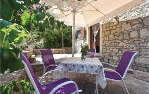 a table with purple chairs and an umbrella at Two-Bedroom Apartment In Stomorska in Stomorska