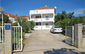 a white house with a car parked in front of it at Apartment Drfranje Tudmana I in Turanj
