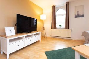 un salon avec une télévision à écran plat sur un meuble blanc dans l'établissement Pretty Home Skyline Work & Stay, à Chemnitz