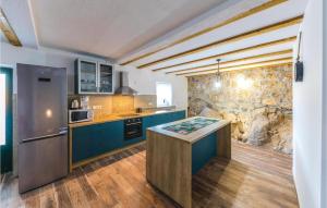a kitchen with blue cabinets and a stone wall at Two-Bedroom Holiday Home In Ljubitovica in Ljubitovica