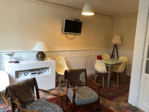 トゥルヴィル・シュル・メールにあるMaison 5 chambres, jardinet, accès plageの椅子、テーブル、壁掛けテレビが備わる客室です。