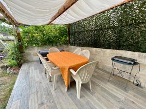 een tafel en stoelen met een oranje kleed op een terras bij Studio au calme climatisé avec terrasse in Paillet