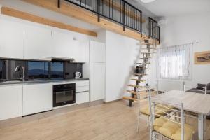 a kitchen and dining room with white cabinets and a wooden table at Villa Vuka in Omišalj