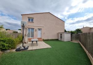 een huis met een gazon met een stoel en een paraplu bij Maison in Sainte-Marie-la-Mer
