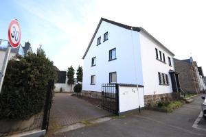 a white house with a fence next to a street at Design-Ferienwohnung Ahrweiler WiFi Parken Zentral NEU in Bad Neuenahr-Ahrweiler