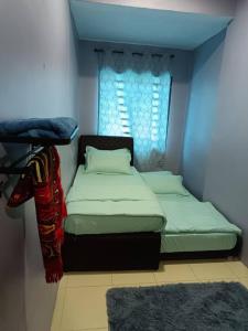 a small bedroom with two beds and a window at Homestay Lyn Impian in Tanjung Rambutan