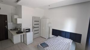 a white bedroom with a bed and a desk and a desk at Apartamenty Micadas in Piaseczno