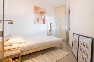 a white bedroom with a bed and a table at un passo dalla torre in Pisa