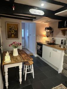 a kitchen with a table with a vase of flowers on it at Love Lane Cottage Dolgellau in Dolgellau