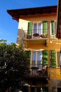a building with green shutters and chairs on a balcony at B&B Casa al Mulino in Cannero Riviera