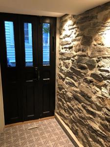 un couloir avec un mur en pierre et une porte noire dans l'établissement Studio above Bryggen with local charm, à Bergen