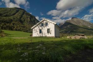 a white house in a field with a mountain at Hansali Holiday Home in Fjarland