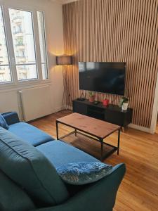 een woonkamer met een blauwe bank en een tv bij View sur la Seine in Parijs