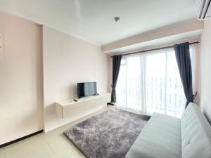 a bedroom with a bed and a tv and a window at Beautiful and Clean 2BR Apartment at Gateway Pasteur Bandung By Travelio in Bandung