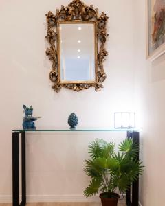 a mirror on a wall above a table with a plant at Politeama Charming Apartment in Palermo