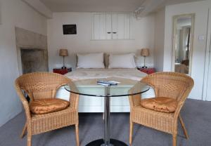 a bedroom with a bed and a glass table with two chairs at Longbridge House in Shepton Mallet