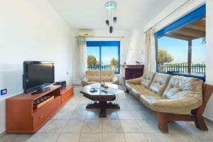 a living room with a couch and a flat screen tv at Stegna House Sea View in Archangelos