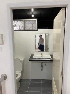 a person taking a picture of a bathroom with a sink at Wonder House in Hat Yai
