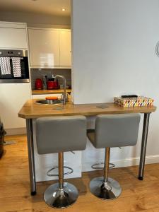 a kitchen with a sink and two bar stools at Jaskar studio 2 in Cheltenham +1 photo